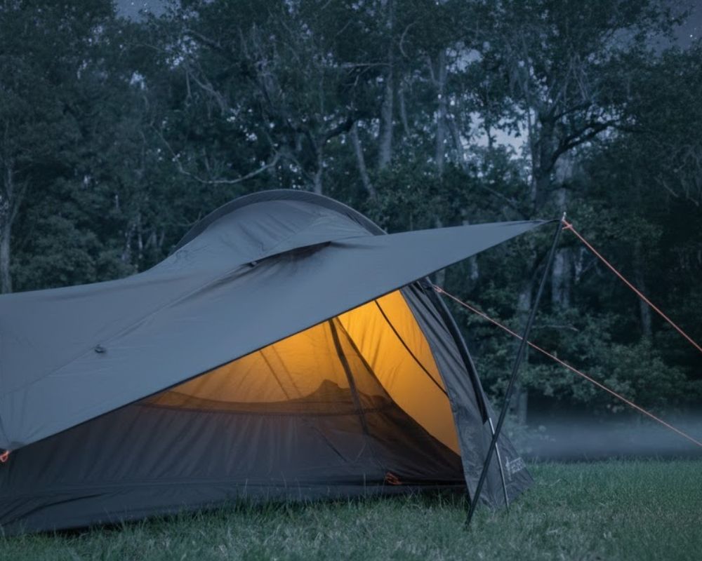 Solo Peak Tent illuminata durante un bivacco notturno, che mostra l'ampio ingresso laterale e lo spazio interno per dormire comodamente dopo una tappa in bici.