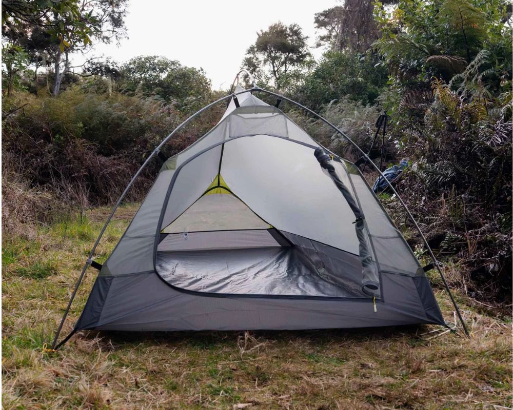 Tenda Tracker Pro 2 montata su un terreno erboso in un bosco, vista prospettica che mostra la paleria esterna e l'abitacolo grigio.